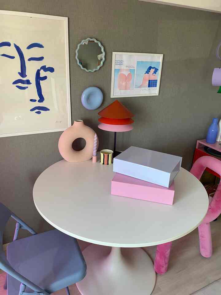 Nordic style dining room with a white round table and pink decor items against a gray wall