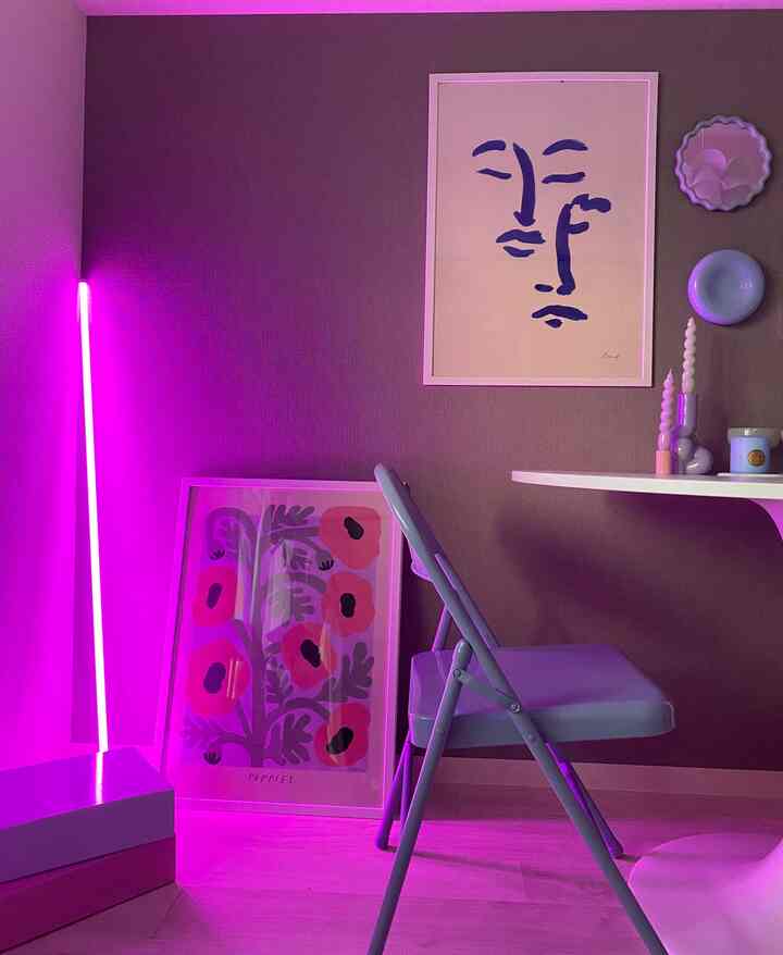 ピンクのネオンチューブ照明がある北欧風リビング、円形のダイニングテーブルと折りたたみ椅子が配置されたミニマルな空間