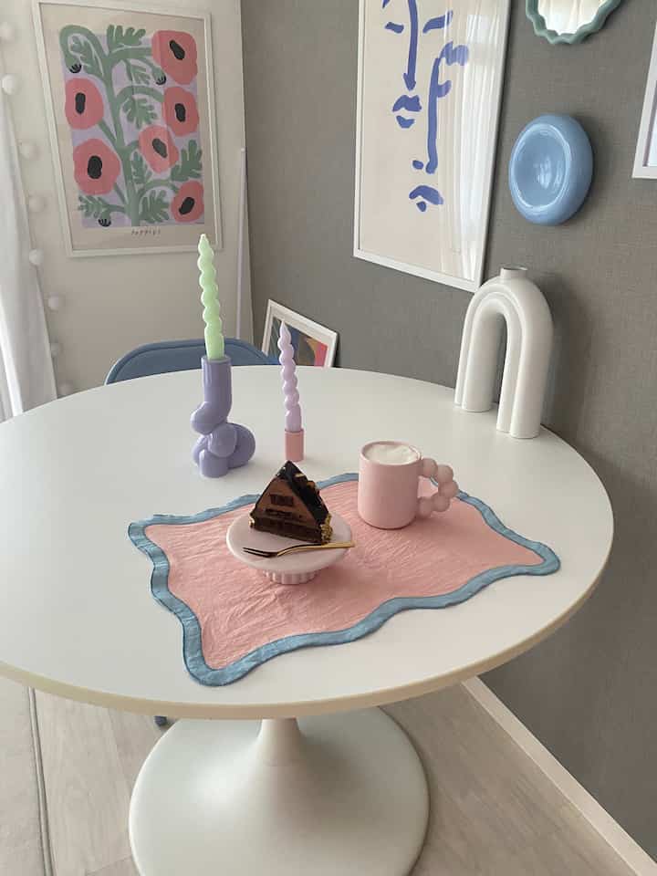 白とピンクの色調のダイニング、丸テーブルの上にキャンドルとケーキが配置された印象的な空間