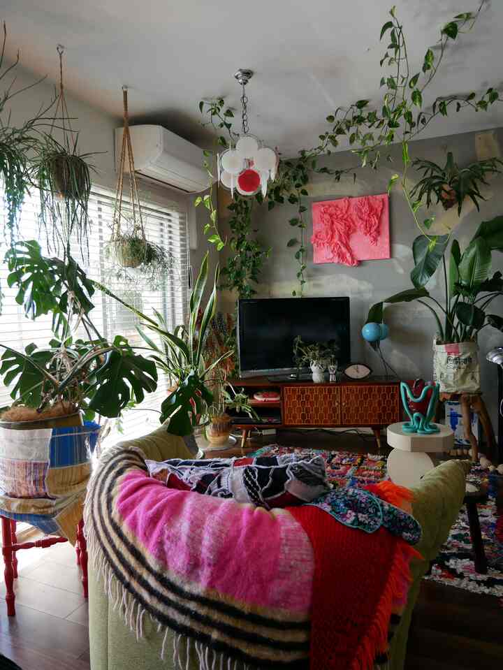 緑豊かな植物とカラフルなテキスタイルが配置されたリビング、明るく自然な雰囲気のあるインテリア