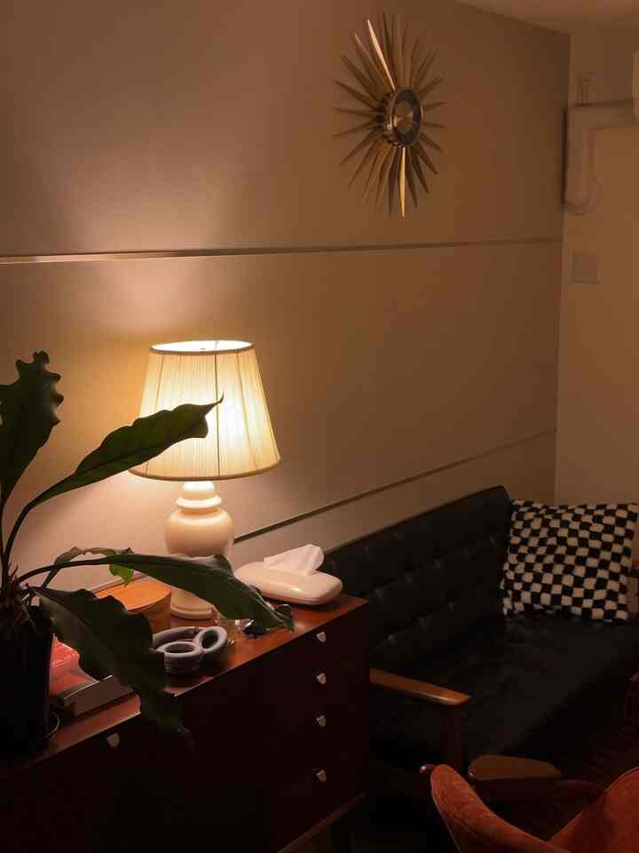 暖かいベージュ色の壁と木製家具が配置されたモダンなリビング、テーブルランプと植物が印象的な雰囲気を作り出すインテリア