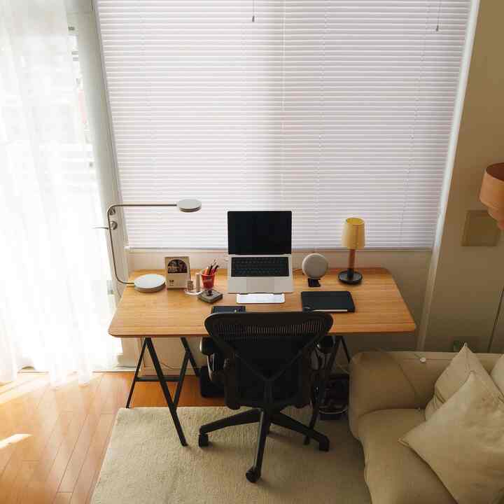 A white and wood tone studio home office featuring a functional desk and Aeron chair with minimal design