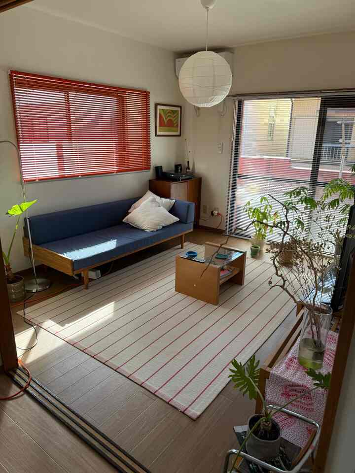 Warm mid-century modern living room featuring orange blinds, navy sofa, and wooden furniture