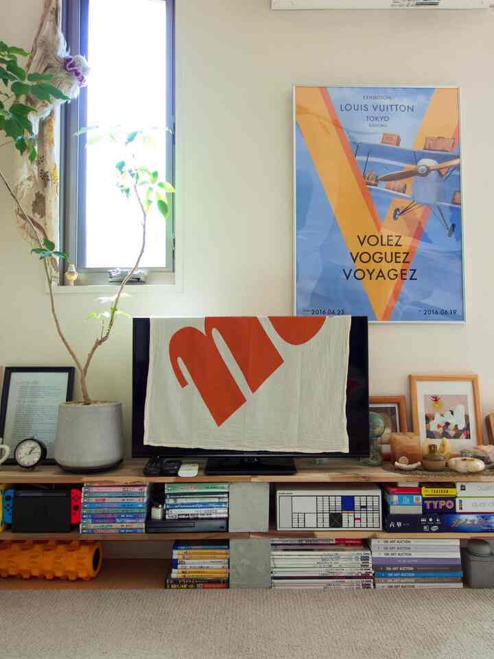 ナチュラルな木目調とミッドセンチュリーモダンの1LDKリビング、大きな植物とポスターが配置された印象的な空間