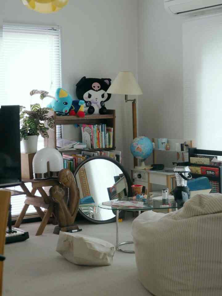 明るいナチュラルトーンのリビング、ベージュの大きなビーズクッション、ガラスのコーヒーテーブル、本棚と子どものおもちゃが置かれた雰囲気のある空間