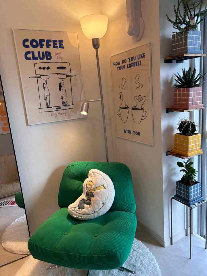 白い壁とグリーンのアームチェアが配置された北欧風の居心地の良いおうちカフェコーナー、コーヒーポスターと植物が際立つインテリア