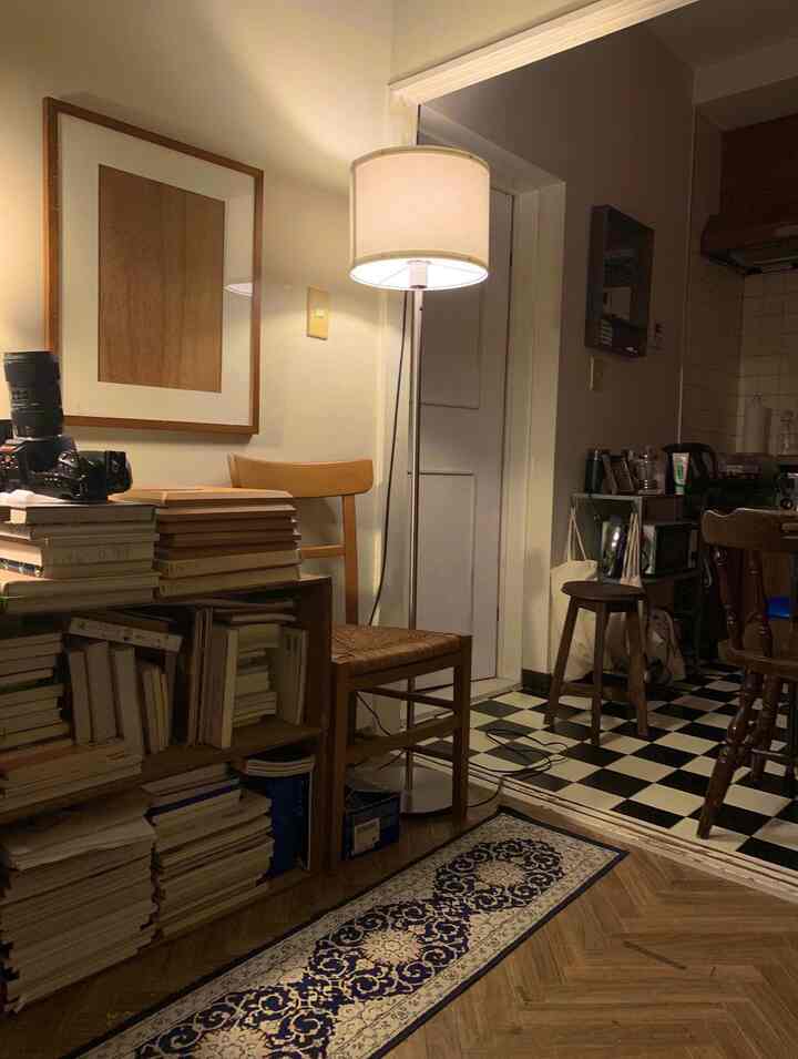 Brown and black toned dining area featuring a floor lamp and bookshelf with cozy retro interior style