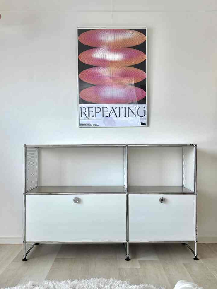 白とグレーのトーンのミニマルな空間、中型の収納キャビネットと抽象的なポスターが配置された清潔感のあるインテリア