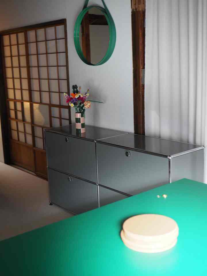 グリーンの色調が印象的な玄関スペース、中央にサイドボードと壁掛けミラー、花瓶が配置されたすっきりとしたモダンなインテリア