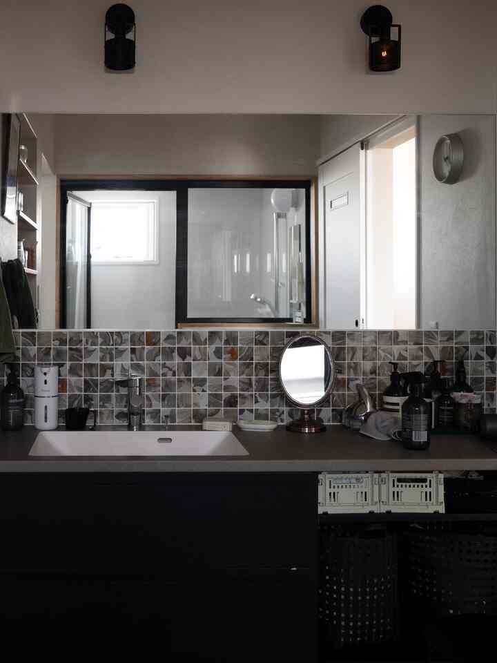 Gray and white bathroom featuring sink, storage boxes, and wall sconces in a minimalistic setting