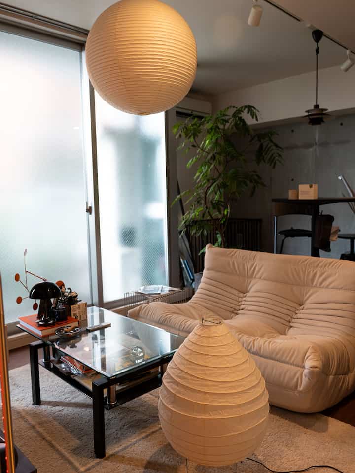 Beige-toned Mid-Century Modern living room featuring a ligne roset Togo sofa, pendant light, coffee table, and plants creating a cozy atmosphere
