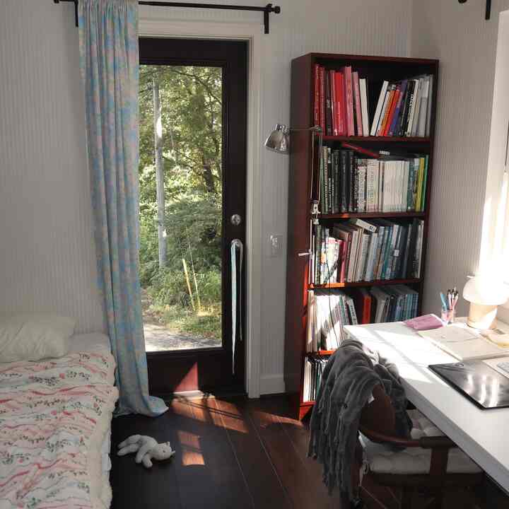 白とダークブラウンの色調の7畳の部屋、ベッド、書斎机、本棚が配置された自然で落ち着いたワークスペース