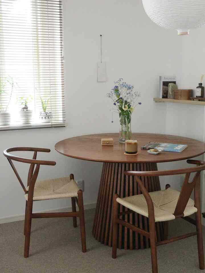 白い壁と木目調の丸いテーブルと椅子が配置された、赤ちゃんと暮らす二人暮らし向けのダイニングルーム