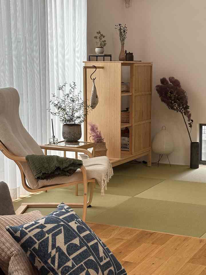 ナチュラルな木目調と緑の畳が調和したリビング、ベージュのアームチェアとサイドテーブルが配置された落ち着いた雰囲気のインテリア