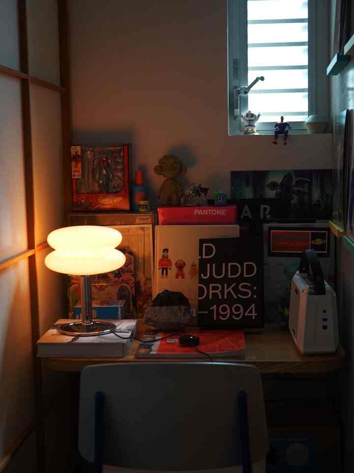 Warm monotone toned small studio workspace featuring wood tone desk and table lamp with cozy atmosphere