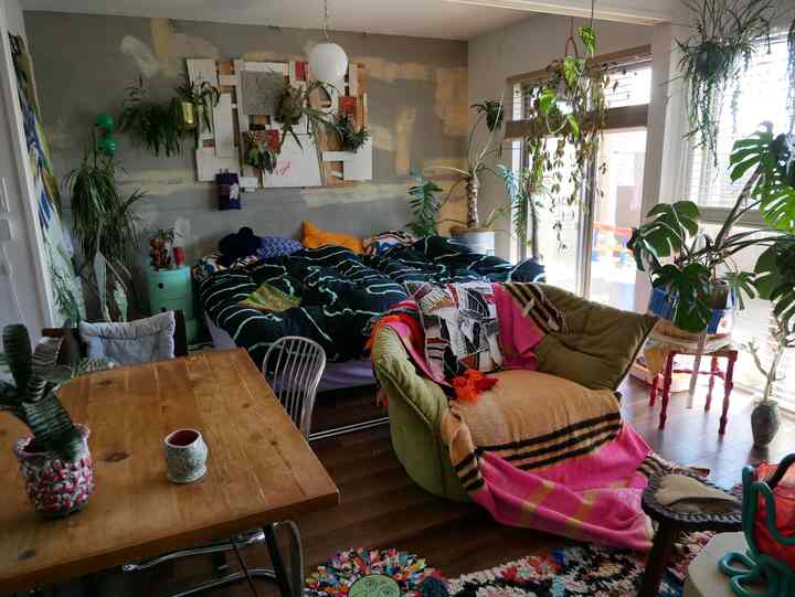 Natural-toned dining and living room featuring sofa and bed with vintage style decor