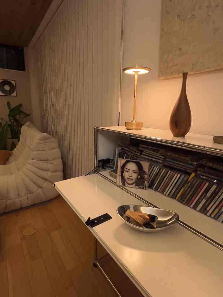 柔らかなブラウンとホワイトの色調のリビング、ミッドセンチュリーモダンスタイルの2人掛けソファとサイドボード、テーブルランプとアートが配置された雰囲気のある空間