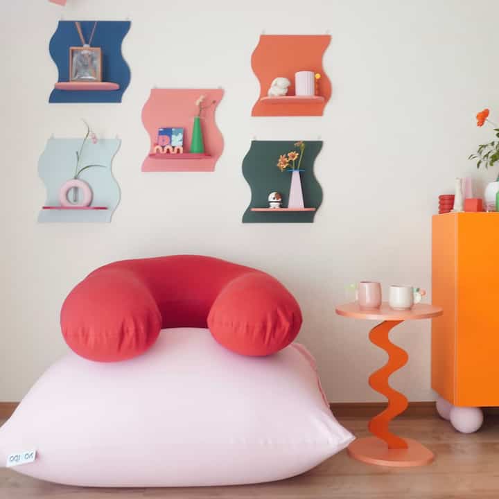 Colorful space featuring pink bean bag, orange side table, and artistic wall decor with playful atmosphere