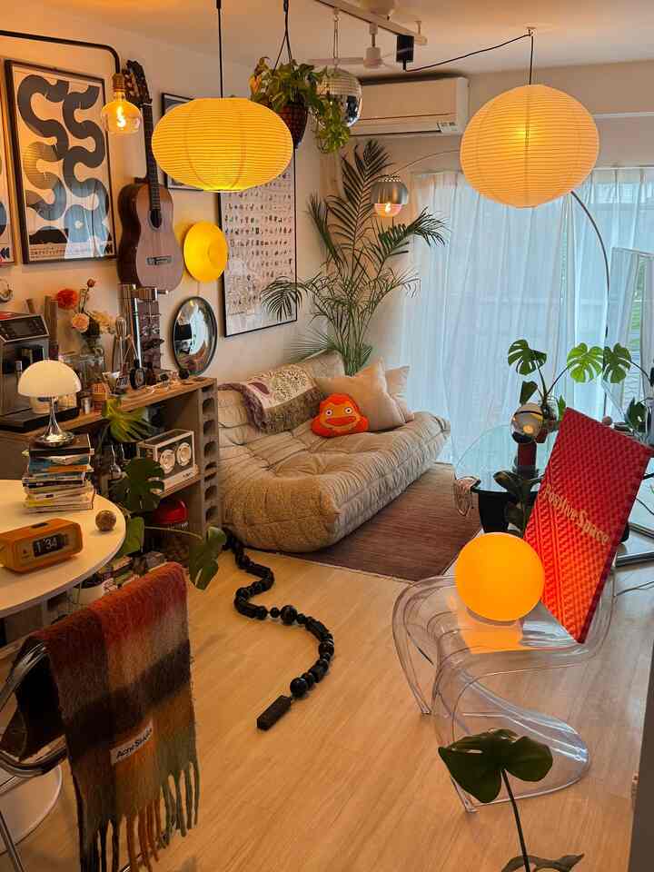 A warm yellow-lit Mid-Century Modern living room featuring a beige sofa, multiple plants, and natural materials