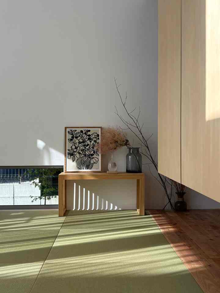 ナチュラルな木目調と爽やかなグリーンの畳が調和するリビング、シンプルな木製ベンチとアートポスターが配置された落ち着いた雰囲気のインテリア