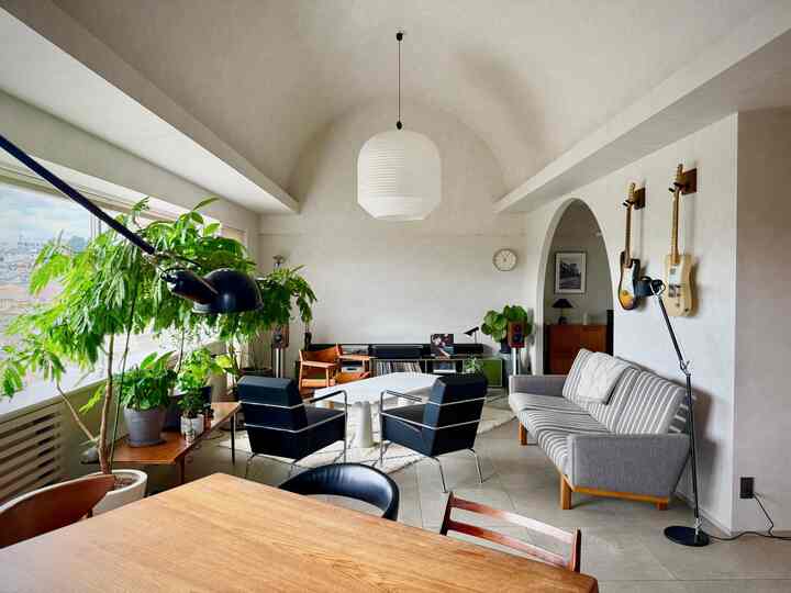 白とナチュラルトーンのリビング、ミッドセンチュリーモダンの家具と多くの植物が配置された雰囲気のあるインテリア