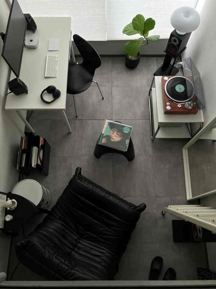 モノトーンの黒と白のホームオフィス空間、デスクと快適なレザーソファ、レコードプレーヤーと植物が調和したシンプルなインテリア