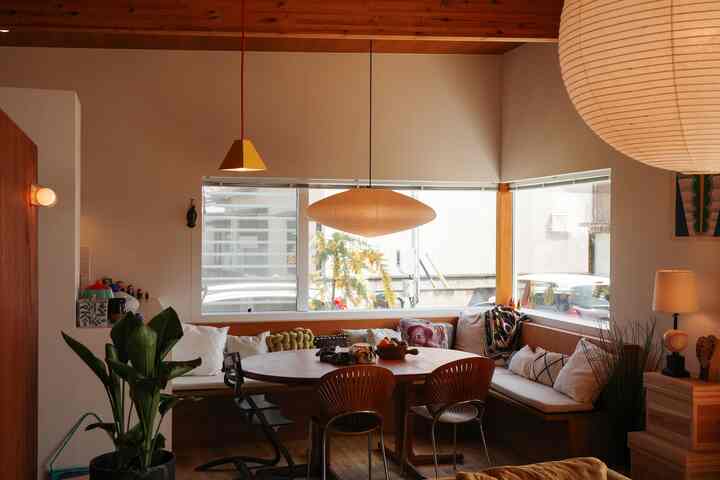 Wood tone and white mid-century modern dining room featuring corner bench seating and pendant lights creating a cozy atmosphere