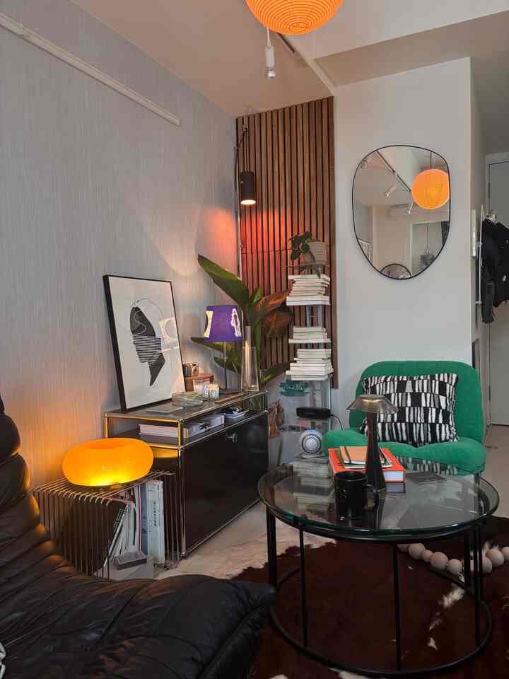 Natural modern 8-tatami room featuring black leather sofa, green armchair, sideboard, and warm indirect lighting creating cozy living space