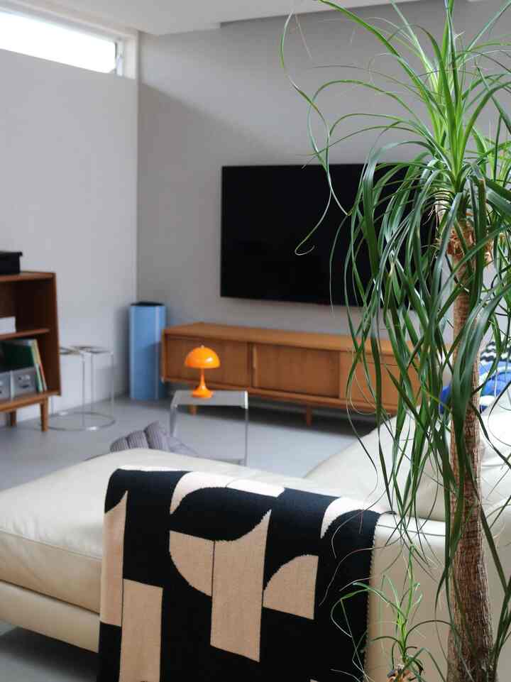 白い壁とソファ、木製テレビ台が配置された北欧風の雰囲気あるリビング