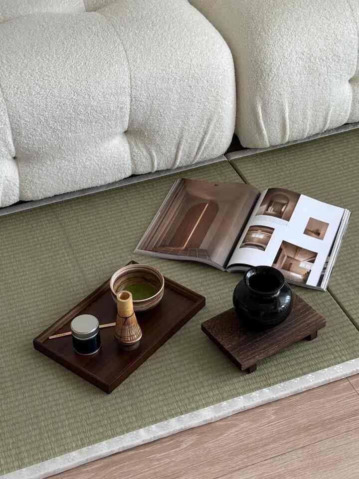 ナチュラルカラーのリビング、白いソファと緑の畳、木製のトレイと花瓶が配置された落ち着いた雰囲気のインテリア