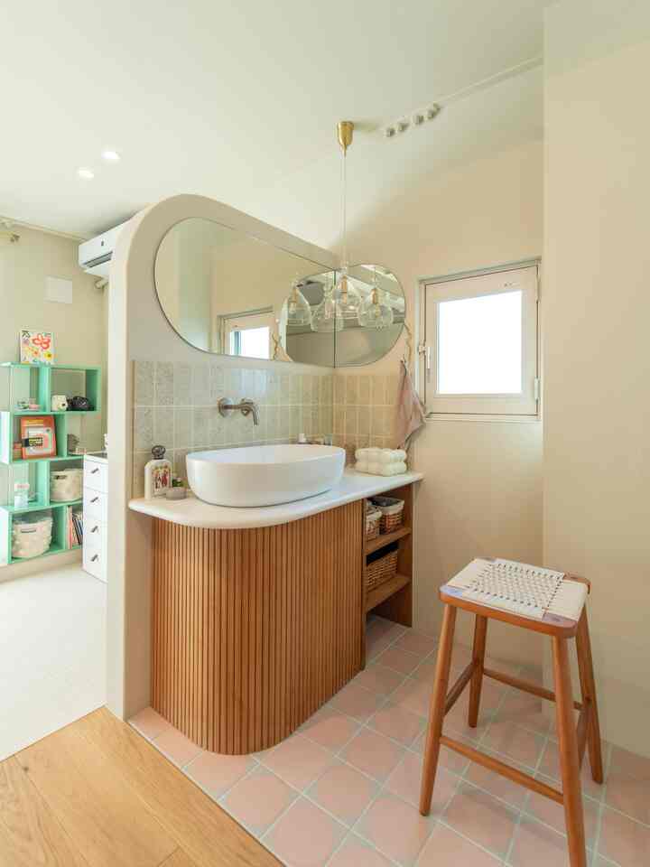 White and beige tone bathroom featuring wood tone storage cabinet, a wooden stool, and pendant lights creating a natural atmosphere