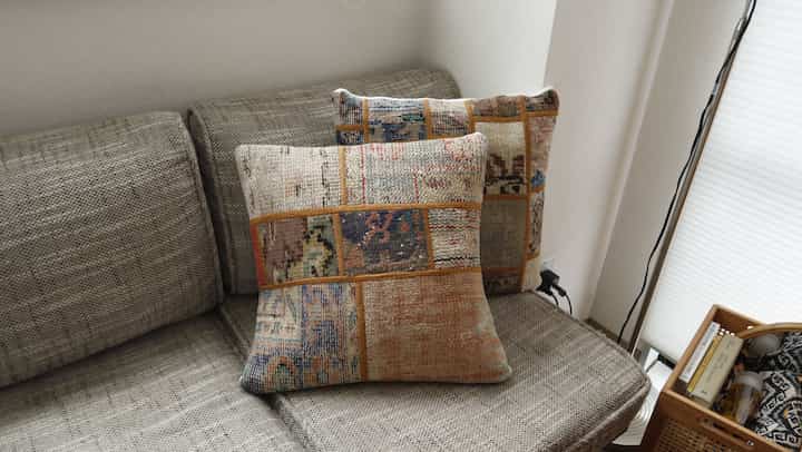 Natural brown tone veranda space featuring a sofa with patchwork cushions creating a cozy atmosphere