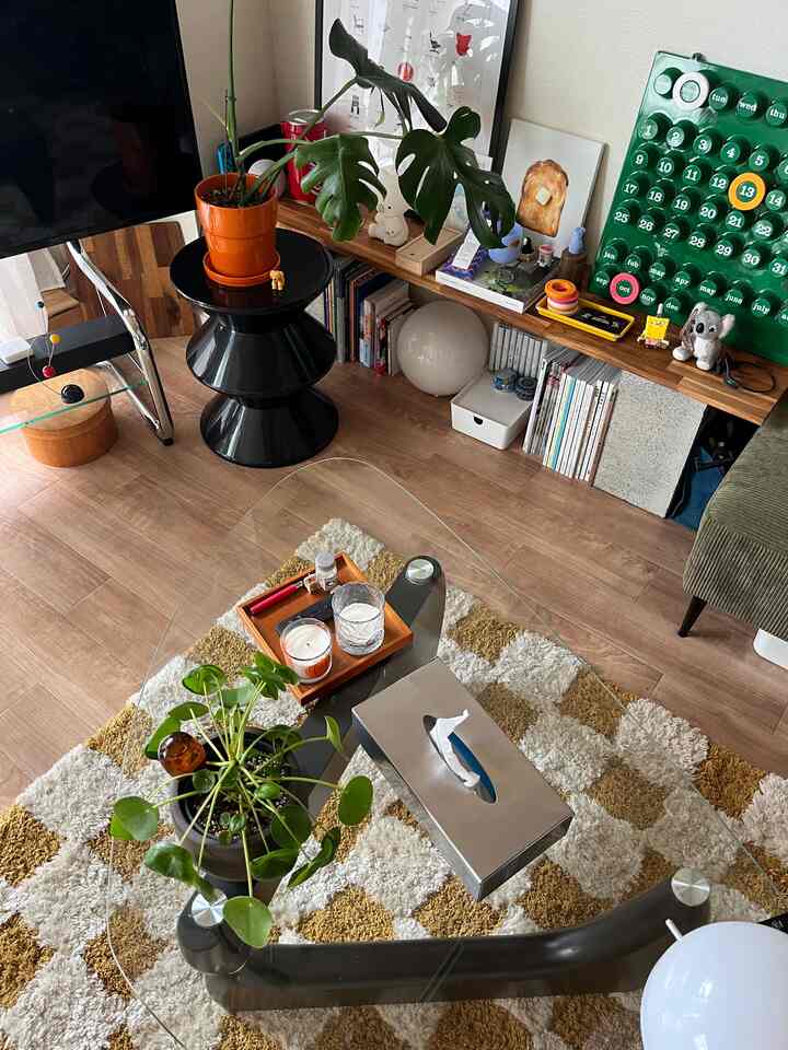 ナチュラルな色調のリビング、ガラスのコーヒーテーブルに多様な植物が配置されたシンプルな空間