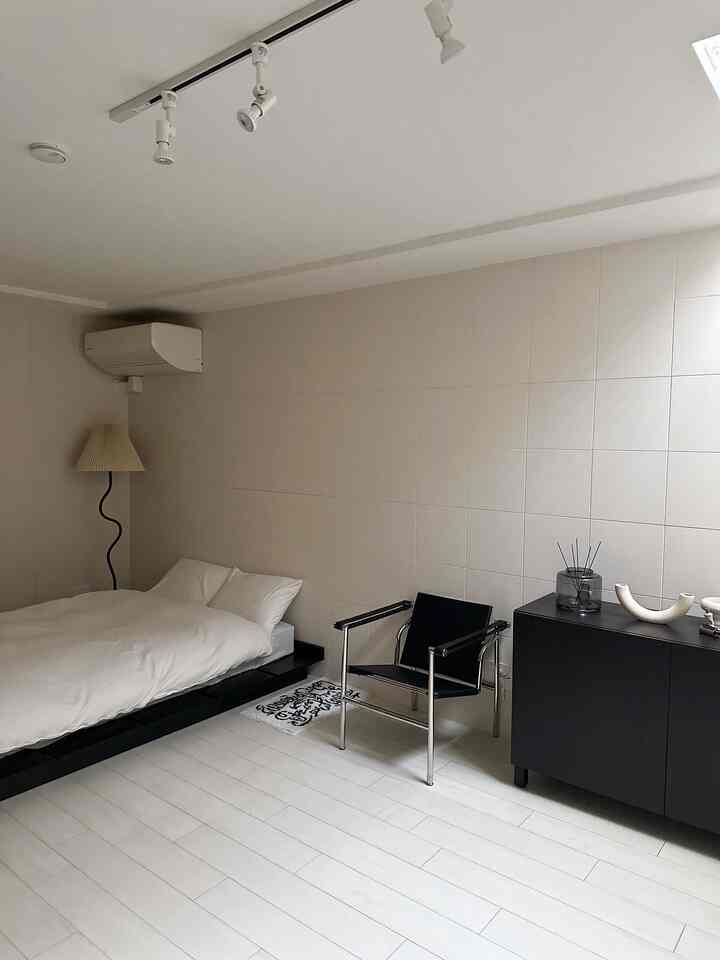 落ち着いたホワイトとブラックの組み合わせの寝室、低いベッドとシンプルな家具が配置されたミニマルな空間