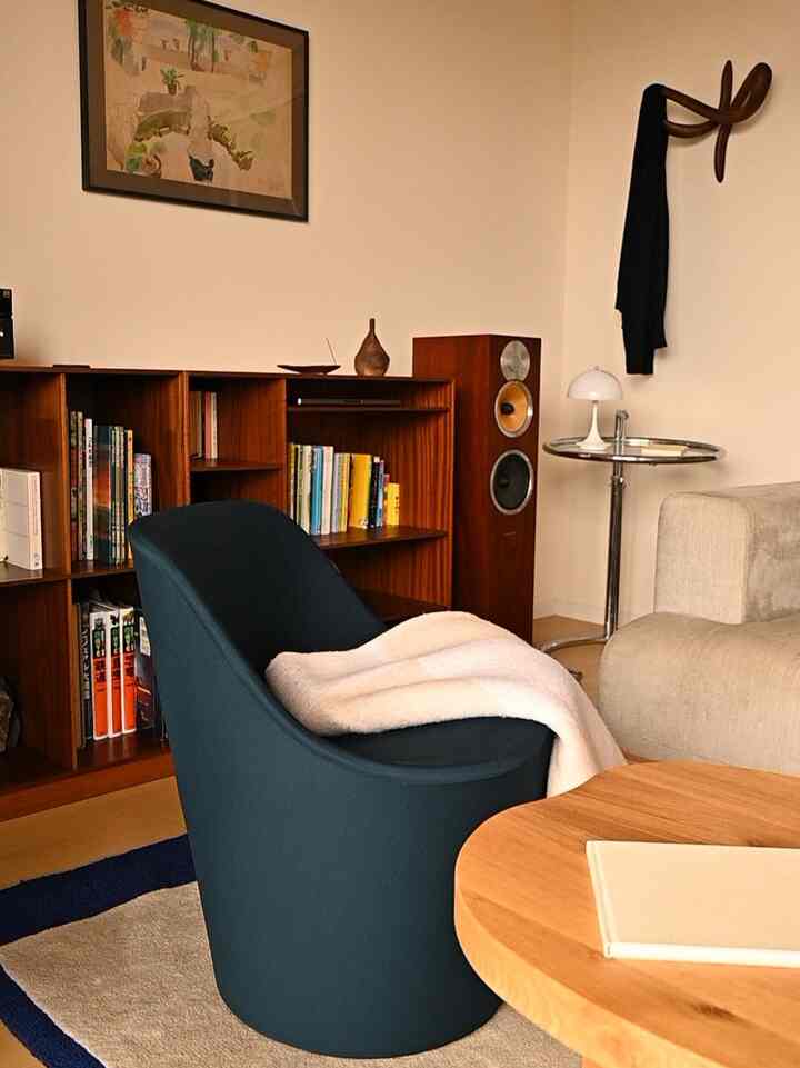 ネイビーのラウンジチェアとブラウンの本棚が配置されたナチュラルモダンなリビング、落ち着いた雰囲気のインテリア