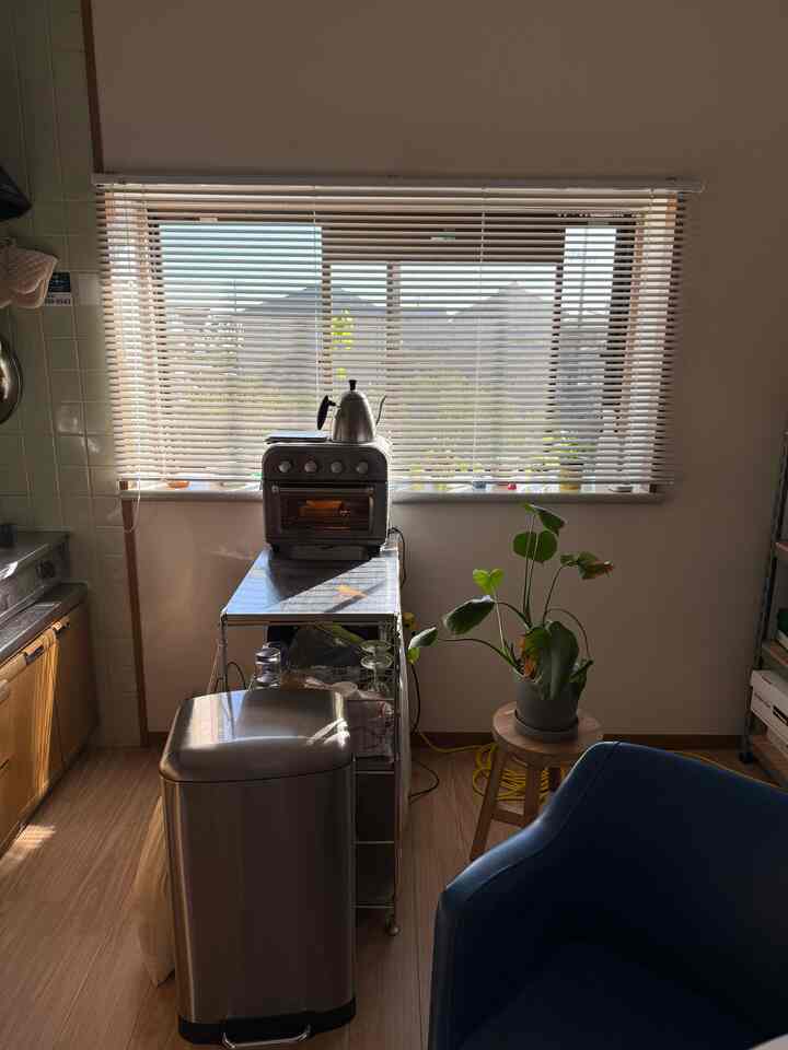 Kitchen space with orange blinds, blue sofa, wooden stool and plant creating a warm cozy atmosphere