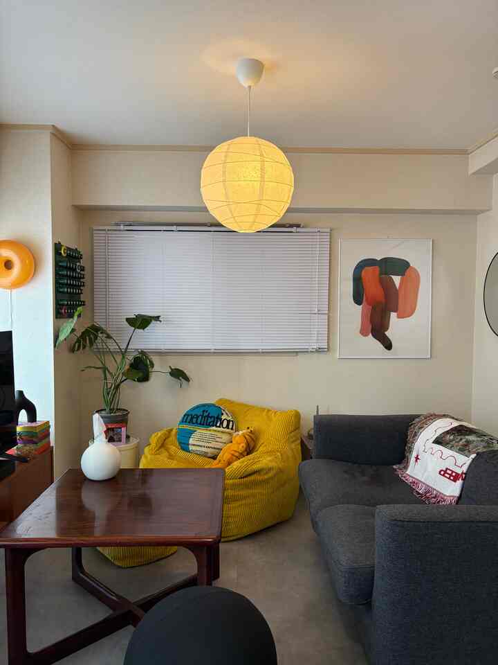 黄色のビーズクッションとダークグレーのソファが配置された12畳のリビング、暖かみのあるミッドセンチュリーモダンの雰囲気のあるインテリア