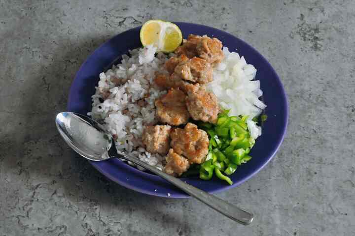 紺色の皿に盛られたご飯と肉、生の玉ねぎ、ピーマンのシンプルな食事