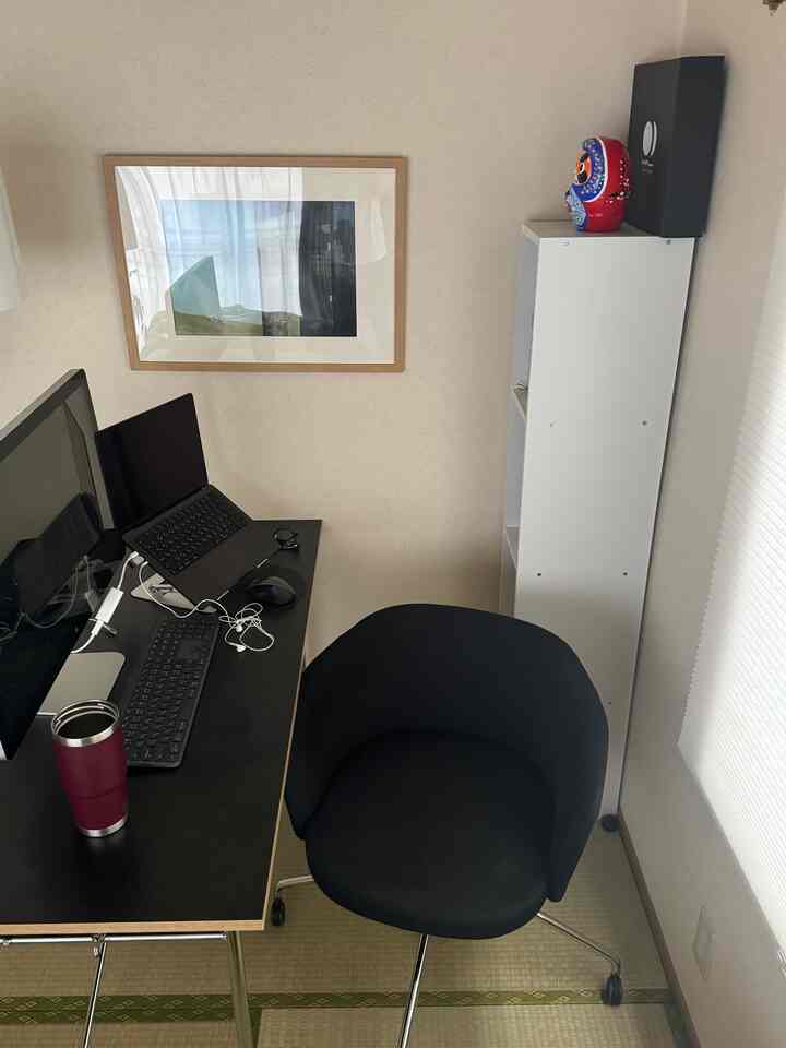 白い壁と黒い机、オフィスチェアが配置されたコンパクトなホームオフィスの雰囲気あるインテリア