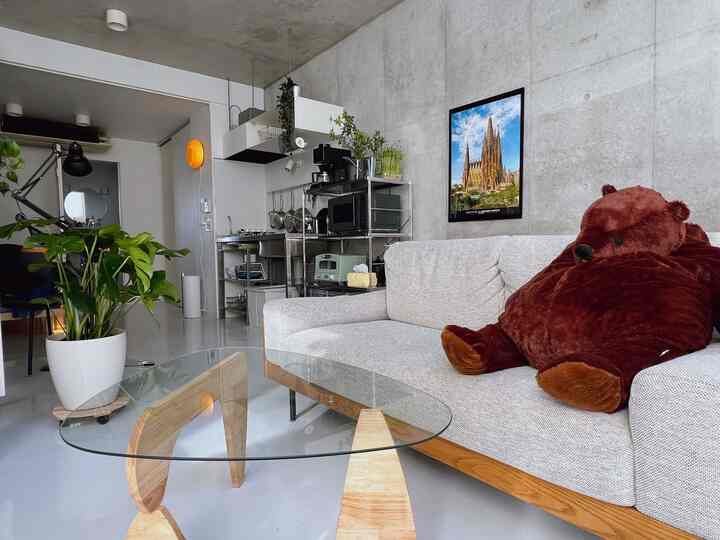 Minimal modern living room with white and natural tones featuring a large bear plush for cozy atmosphere