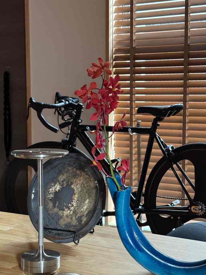 木目調のテーブルに花瓶と自転車が配置された一人暮らしの狭い1LDKのインテリア