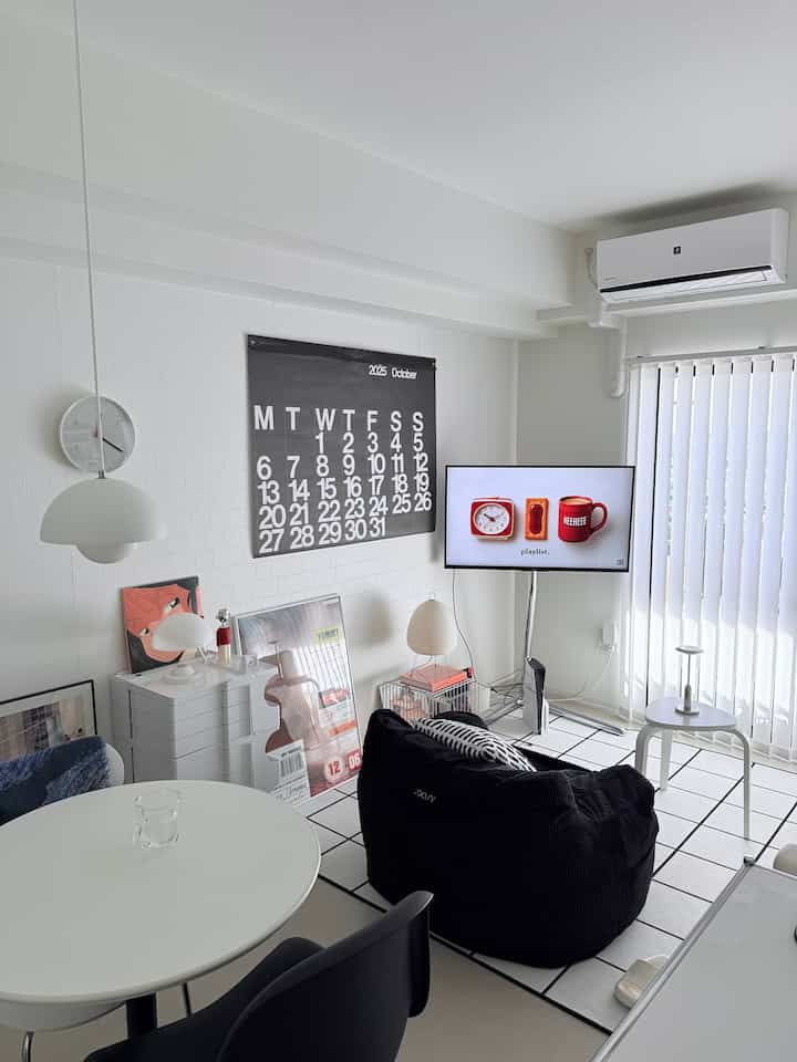 白と黒のトーンのリビング、黒のビーズクッションとペンダントライトが配置されたモダンでシンプルな空間