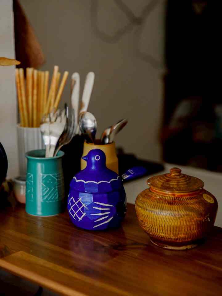 Natural tone wooden table featuring kitchen utensils and folk art-style decorative objects