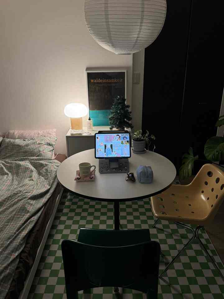 White and green toned studio apartment featuring bed, round table, and soft lighting creating a cozy space