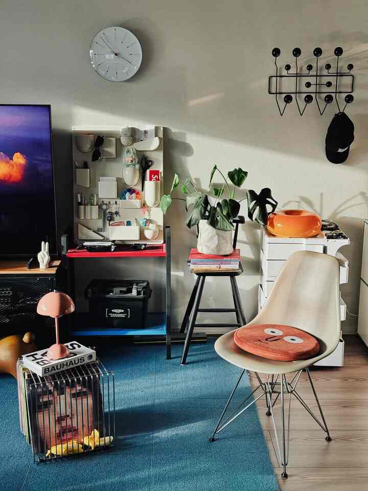 ネイビーカーペットとベージュのイームズチェアが配置された明るくモダンなリビングルーム