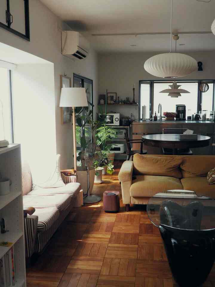 暖かみのある木目調とミッドセンチュリーモダンスタイルのリビング・ダイニング空間、マスタード色のソファとパーケットフローリングが映える居心地の良いインテリア