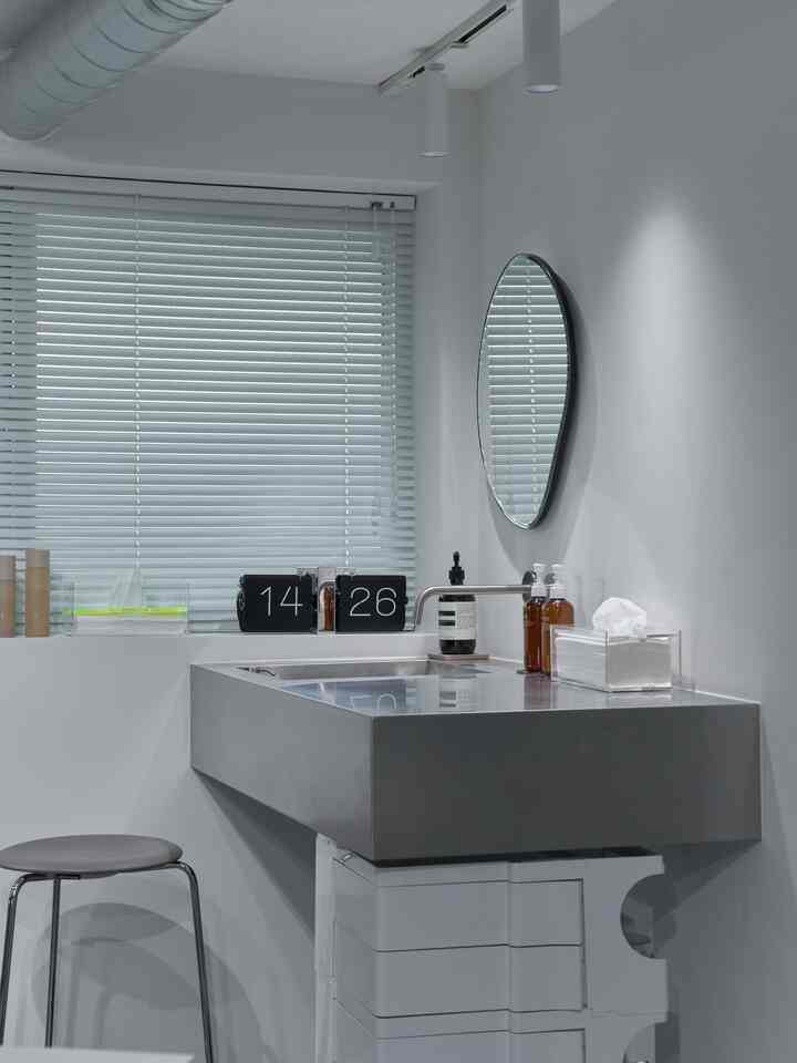 白を基調としたキッチンスペース、ステンレスシンクとスツールが配置されたミニマルなインテリア