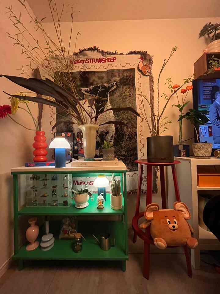 温かみのあるオレンジ色の照明と多様な花瓶、植物が配置された居心地の良い1LDKのミッドセンチュリーモダンなインテリア