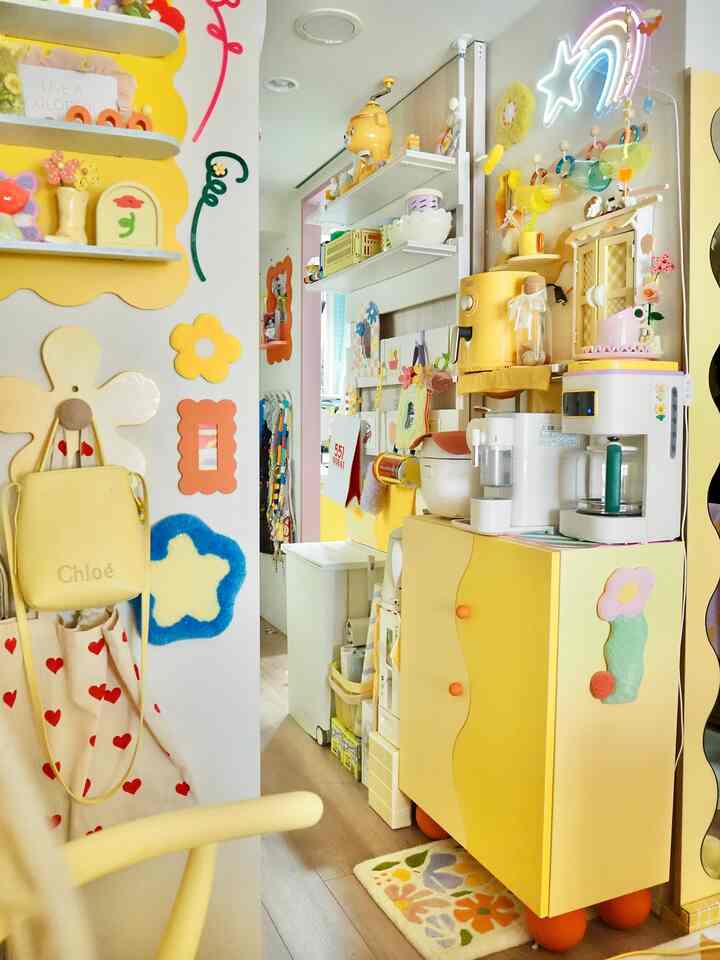 黄色を基調としたキッチンスペース、波型の扉キャビネットやコーヒーメーカー、壁のカラフルな装飾が配された雰囲気のあるインテリア