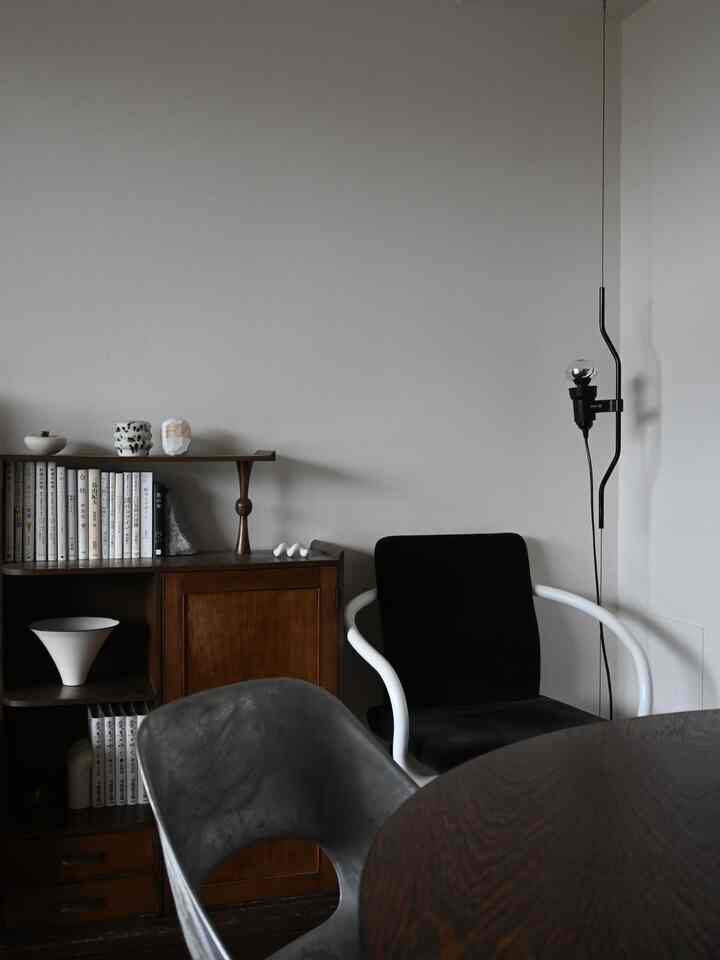 ナチュラルカラーとミッドセンチュリーモダンのスタイルが特徴のダイニング、書棚とアームチェアが置かれたシンプルな空間